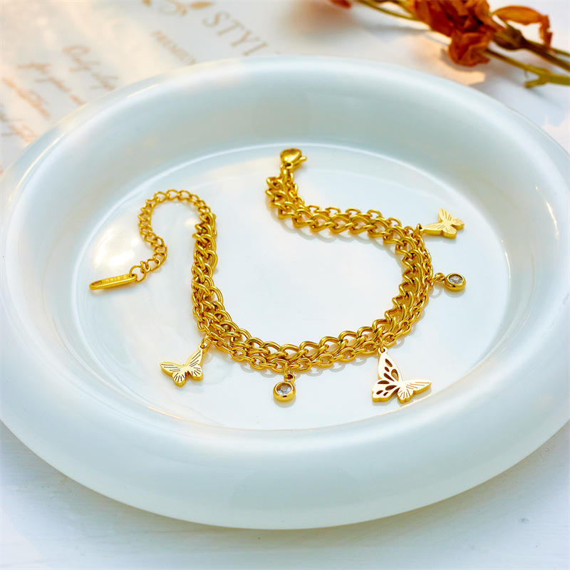 Gold bracelet with charms on a white dish